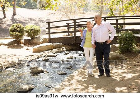 Stock Photo - Senior couple standing beside stream. Fotosearch
