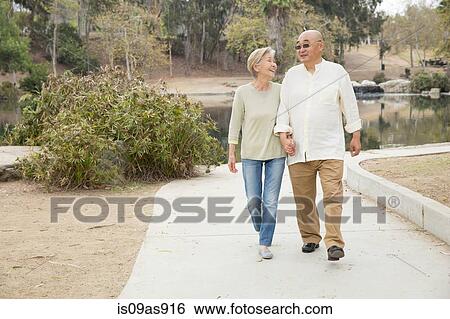 Senior couple walking along pathway, holding hands View Large Photo Image Stock Photograph - Senior couple walking along pathway, holding hands. Fotosearch