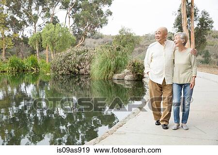 Stock Photo - Senior couple walking beside lake. Fotosearch