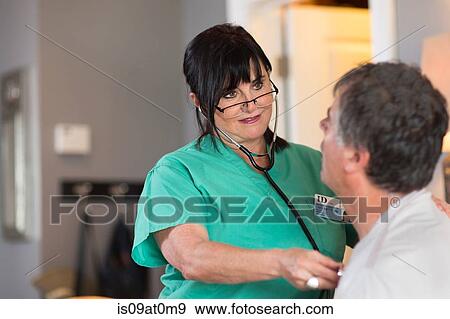 Stock Photo - Senior female nurse checking patient's heart. Fotosearch