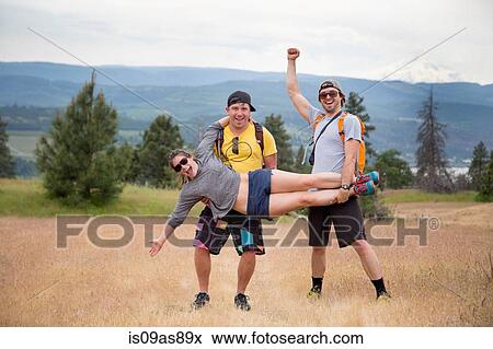 Small group of hikers, fooling around, two men holding woman up, laughing, celebrating View Large Photo Image Stock Photo - Small group of hikers, fooling around, two men holding woman up, laughing, celebrating. Fotosearch