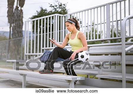 Soccer player using smartphone on bench View Large Photo Image Stock Image - Soccer player using smartphone on bench. Fotosearch