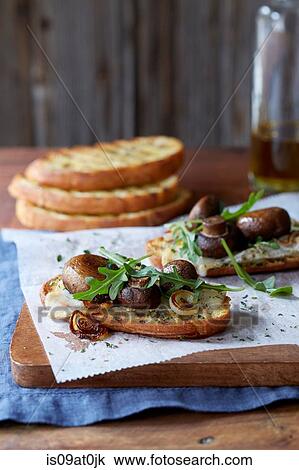 Stock Image - Still life of bruschetta with portobello mushroom roasted cipollini onion, gouda cheese and fresh arugula. Fotosearch