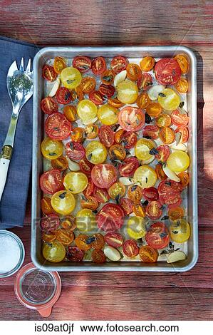 Stock Image - Still life of roasted tomatoes, garlic, oregano and olive oil. Fotosearch