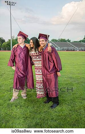 Stock Photograph - Students celebrate graduation with friend. Fotosearch