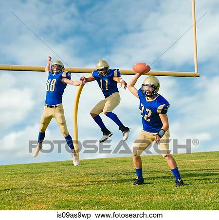 Stock Photography - Team of teenage and adult American footballers practicing next to field goal. Fotosearch