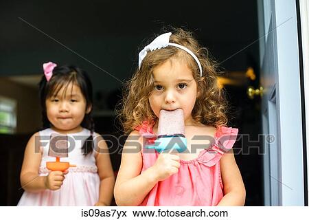 Two young girls eating ice lollies View Large Photo Image Stock Photo - Two young girls eating ice lollies. Fotosearch