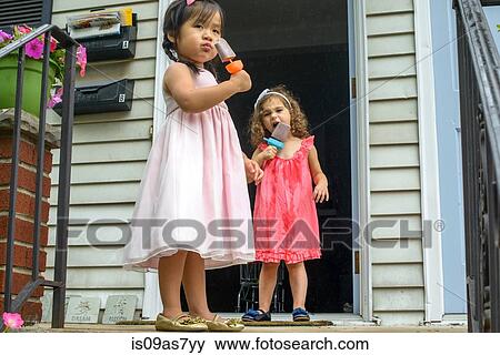 Two young girls eating ice lollies View Large Photo Image Stock Photo - Two young girls eating ice lollies. Fotosearch