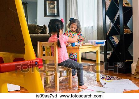 Two young girls sitting at table, making art, using paint View Large Photo Image Stock Image - Two young girls sitting at table, making art, using paint. Fotosearch