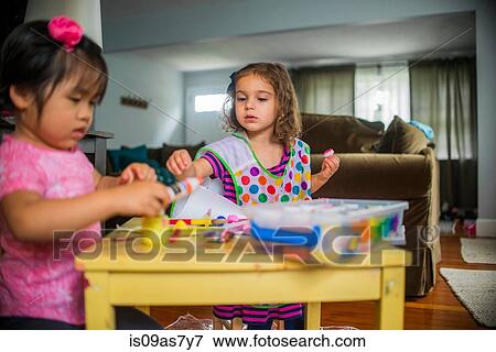 Two young girls sitting at table, making art, using paint View Large Photo Image Stock Photo - Two young girls sitting at table, making art, using paint. Fotosearch