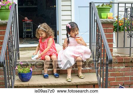 Two young girls, sitting on steps, eating ice lollies View Large Photo Image Stock Image - Two young girls, sitting on steps, eating ice lollies. Fotosearch