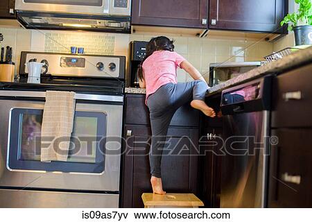 Young girl climbing onto kitchen work surface from stool, rear view View Large Photo Image Stock Photo - Young girl climbing onto kitchen work surface from stool, rear view. Fotosearch
