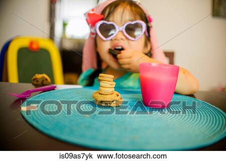 Young girl sitting at table with drink and cookies View Large Photo Image Stock Image - Young girl sitting at table with drink and cookies. Fotosearch