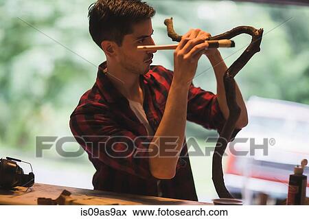 Young man holding paintbrush painting tree branch View Large Photo Image Stock Photo - Young man holding paintbrush painting tree branch. Fotosearch