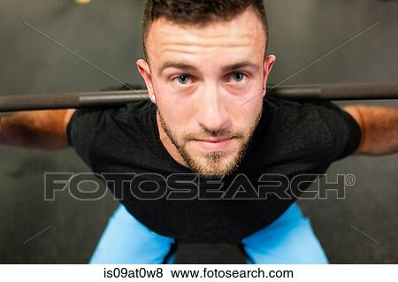 Stock Photo - Young man, lifting weights, close-up. Fotosearch