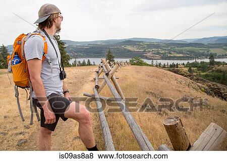 Young man standing on top of mountain, looking at view View Large Photo Image Stock Photo - Young man standing on top of mountain, looking at view. Fotosearch