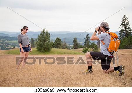 Young man taking photograph of young woman in rural setting View Large Photo Image Stock Image - Young man taking photograph of young woman in rural setting. Fotosearch