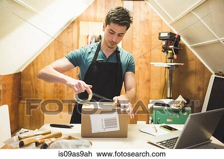 Young man using sticking tape to prepare package for delivery View Large Photo Image Stock Image - Young man using sticking tape to prepare package for delivery. Fotosearch