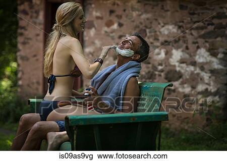 Young woman in bikini sitting on boyfriends lap applying shaving cream at holiday cottage View Large Photo Image Stock Image - Young woman in bikini sitting on boyfriends lap applying shaving cream at holiday cottage. Fotosearch
