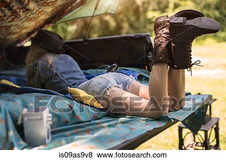 Stock Photo - Young woman lying in pick up boot listening to music on radio. Fotosearch