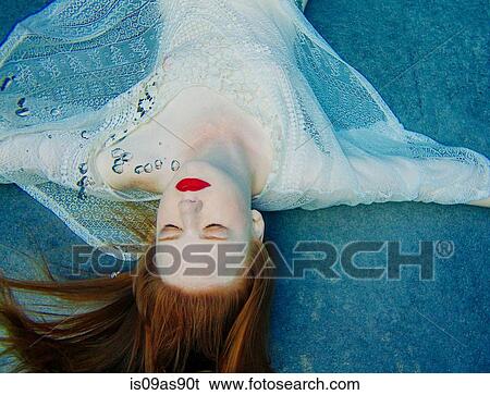 Stock Photograph - Young woman underwater, wearing thin white shirt, overhead view. Fotosearch