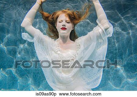 Stock Photography - Young woman underwater, wearing thin white shirt. Fotosearch