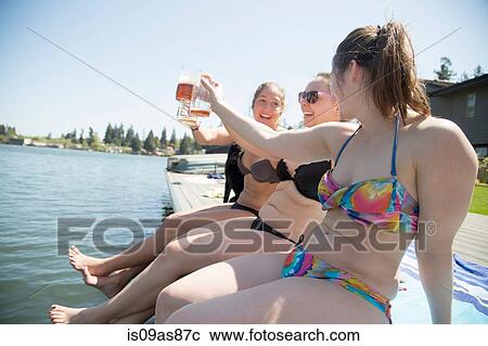 Young women wearing bikinis toasting with beer on waterfront pier, Lake Oswego, Oregon, USA View Large Photo Image Stock Image - Young women wearing bikinis toasting with beer on waterfront pier, Lake Oswego, Oregon, USA. Fotosearch