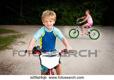 Boy and girl on bicycles looking at camera smiling View Large Photo Image Stock Image - Boy and girl on bicycles looking at camera smiling. Fotosearch