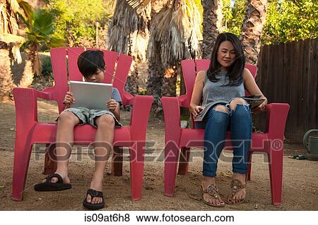 Boy and mother reading digital tablet and magazine in garden View Large Photo Image Stock Photo - Boy and mother reading digital tablet and magazine in garden. Fotosearch