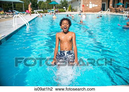 Stock Image - Boy jumping into outdoor swimming pool. Fotosearch