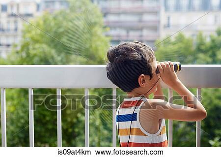 Boy looking through binoculars on balcony View Large Photo Image Picture - Boy looking through binoculars on balcony. Fotosearch
