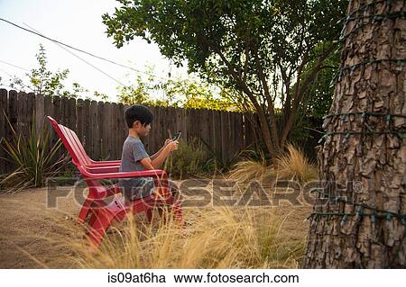 Boy playing game on digital tablet in garden View Large Photo Image Stock Image - Boy playing game on digital tablet in garden. Fotosearch