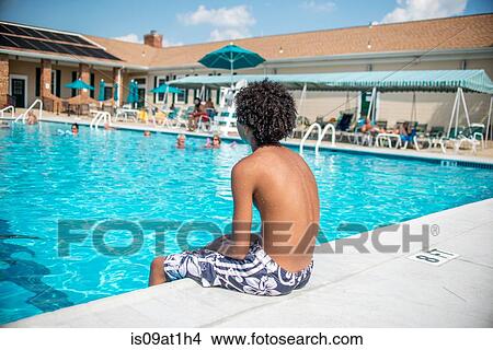 Boy sitting looking out over outdoor swimming pool View Large Photo Image Picture - Boy sitting looking out over outdoor swimming pool. Fotosearch