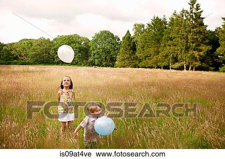 Brother and sister in tall grass playing with balloon View Large Photo Image Stock Image - Brother and sister in tall grass playing with balloon. Fotosearch