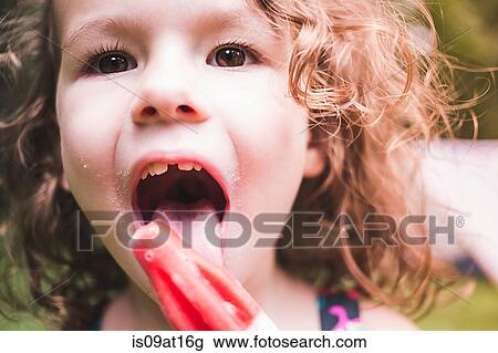 Stock Image - Close up of girl licking ice lolly. Fotosearch