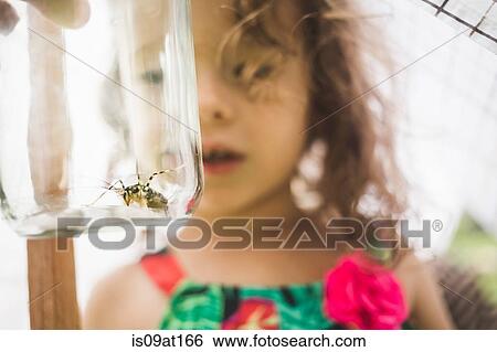 Stock Photograph - Close up of grandfathers hand holding insect in jar for granddaughter. Fotosearch
