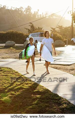 "Couple carrying surfboards, walking towards beach" View Large Photo Image Stock Photograph - "Couple carrying surfboards, walking towards beach". Fotosearch