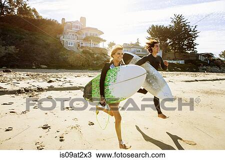 "Couple running towards sea, carrying surfboards" View Large Photo Image Stock Image - "Couple running towards sea, carrying surfboards". Fotosearch