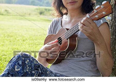 Stock Photo - Cropped image of woman in field playing ukuele. Fotosearch