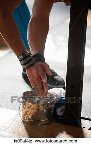 Stock Image - Crossfitter puts powder on hands before workout. Fotosearch
