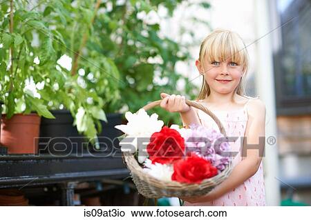 Picture - Cute girl holding fresh flower basket in greenhouse. Fotosearch