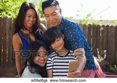Stock Image - Family with boy taking smartphone selfie in garden. Fotosearch