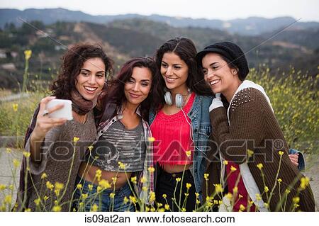 Four adult sisters posing for smartphone selfie on rural road View Large Photo Image Picture - Four adult sisters posing for smartphone selfie on rural road. Fotosearch