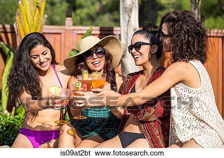 Stock Photograph - Four adult sisters toasting with cocktails at garden party. Fotosearch