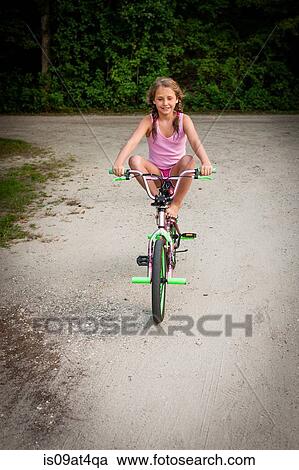 "Front view of girl balancing on bike, legs raised, looking at camera smiling" View Large Photo Image Stock Image - "Front view of girl balancing on bike, legs raised, looking at camera smiling". Fotosearch