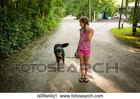 "Front view of girl on dirt road, walking dog, looking over shoulder" View Large Photo Image Stock Image - "Front view of girl on dirt road, walking dog, looking over shoulder". Fotosearch