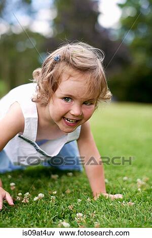 Stock Photo - Front view of girl on hands and knees looking at camera smiling. Fotosearch