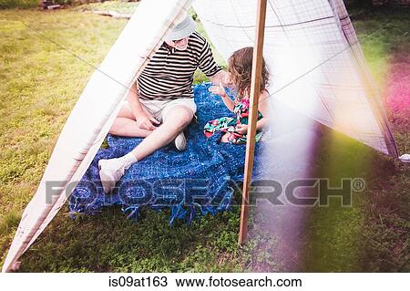 Stock Image - Girl and grandfather playing in homemade garden tent. Fotosearch