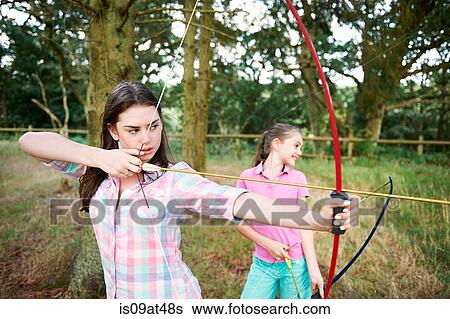 Girl and teenage sister practicing archery View Large Photo Image Stock Photograph - Girl and teenage sister practicing archery. Fotosearch