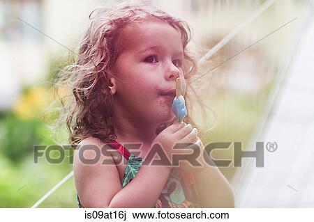 Girl eating melting ice lolly in garden View Large Photo Image Stock Image - Girl eating melting ice lolly in garden. Fotosearch